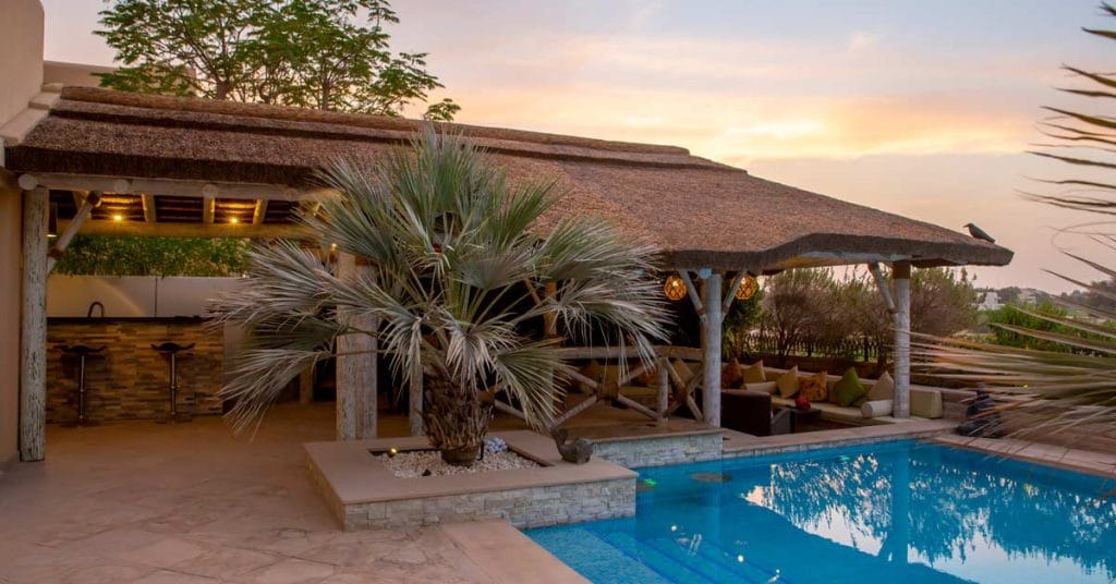Covered dining area and adjacent sunken seating area overlooking the pool and golf course.