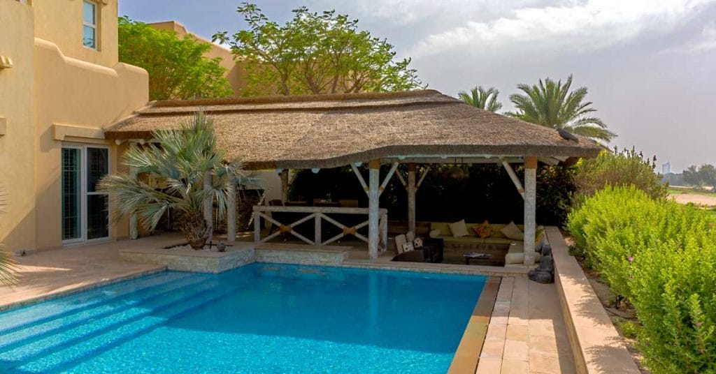 Covered dining area and adjacent sunken seating area overlooking the pool and golf course.