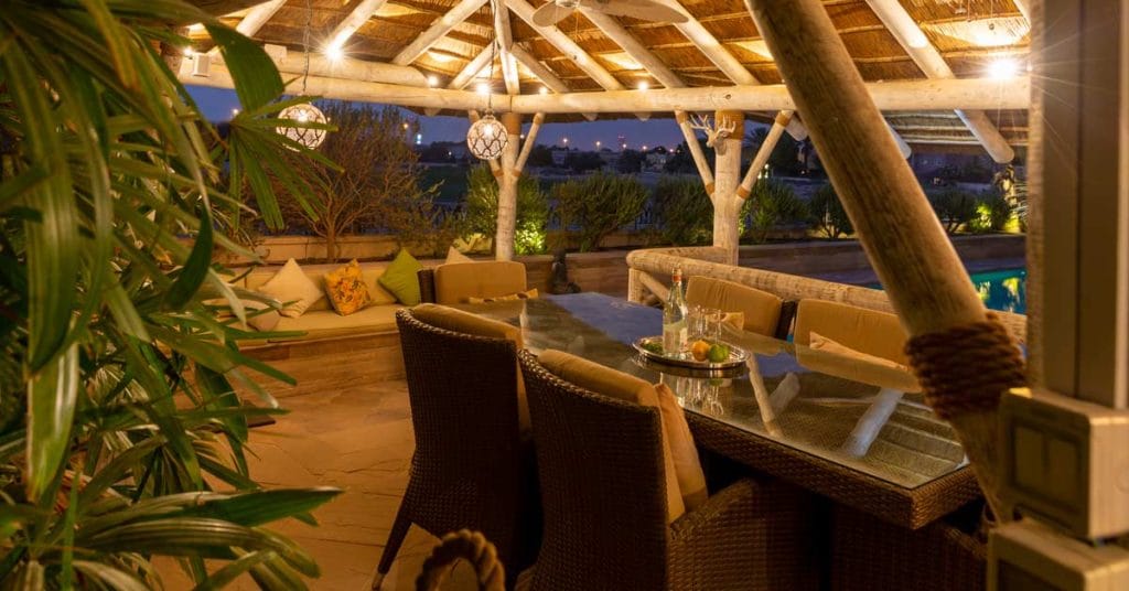Outdoor dining under a modern thatched roof gazebo in a white wash finish