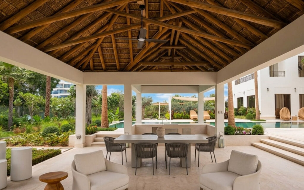 Open-sided thatched entertainment pavilion with swim-up pool bar and modern outdoor seating, Al Barari Dubai residential project by Cape Reed