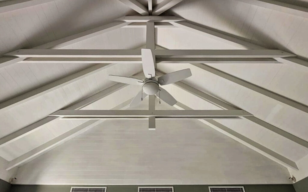 White painted timber ceiling with exposed beam detailing inside a Cape Reed thatched poolhouse, Al Barari Dubai — blending natural thatch with a clean, contemporary interior finish