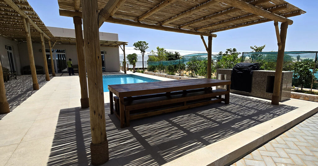Timber pergola over poolside dining bench and table, Abu Dhabi villa
