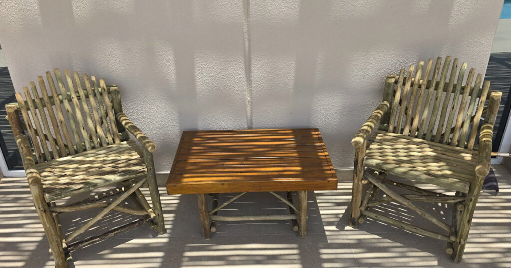 Two handcrafted timber chairs and side table under pergola, Abu Dhabi