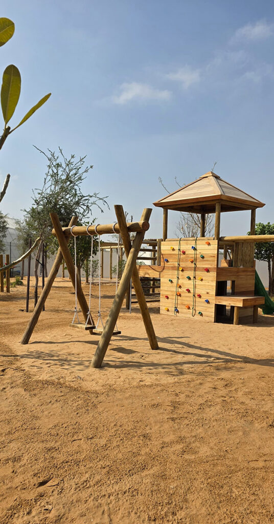 Wooden play structure with swings and climbing wall for children, Abu Dhabi