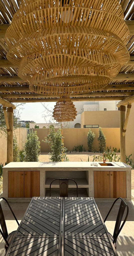 Woven rattan pendant lighting hanging beneath timber pergola beams, Abu Dhabi residence